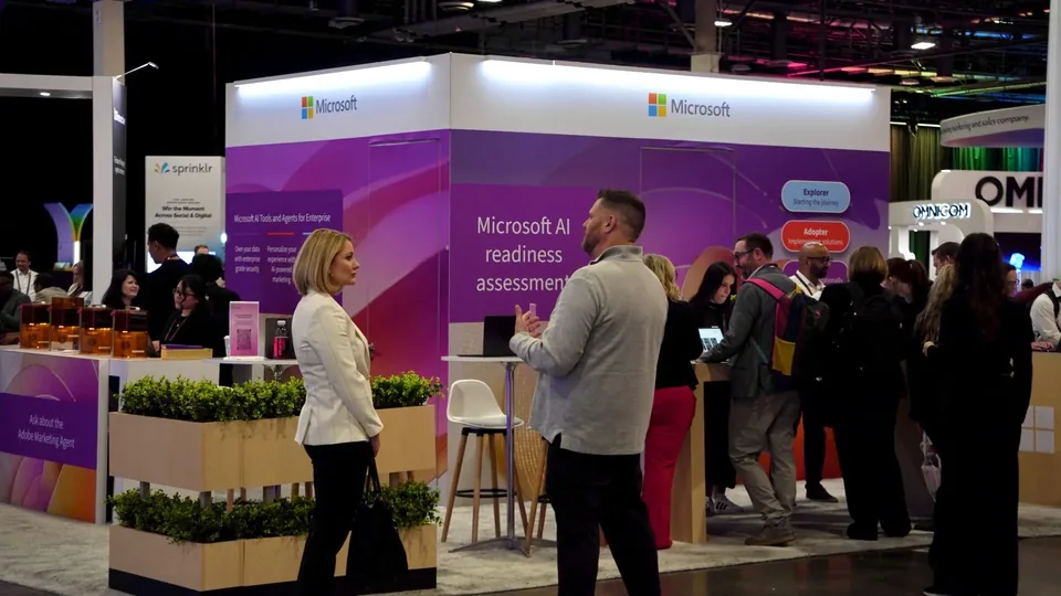Two attendees in conversation at the planted edge of the stand.