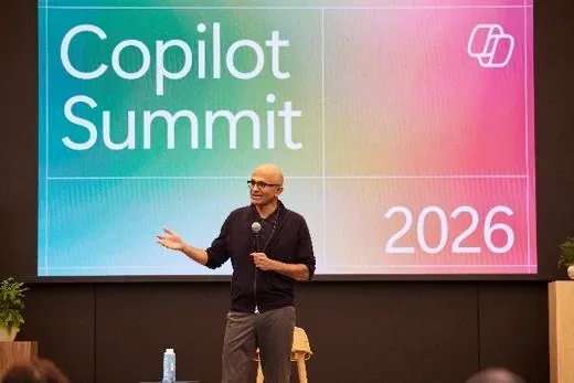 A speaker addressing the room in front of a 'Copilot Summit 2026' title screen.