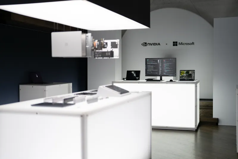 Lit white plinths carrying devices across the briefing floor, the NVIDIA and Microsoft lockup on the wall beyond.