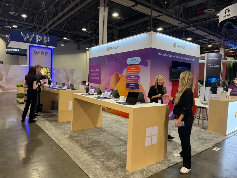 Demo tables along the stand, partner signage on the hall walls beyond.