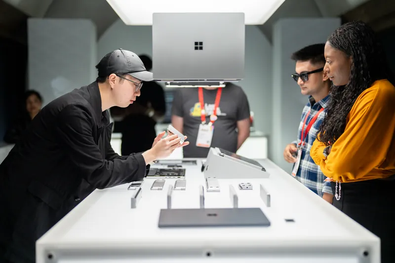A host walking two guests through a Surface device across the display table.