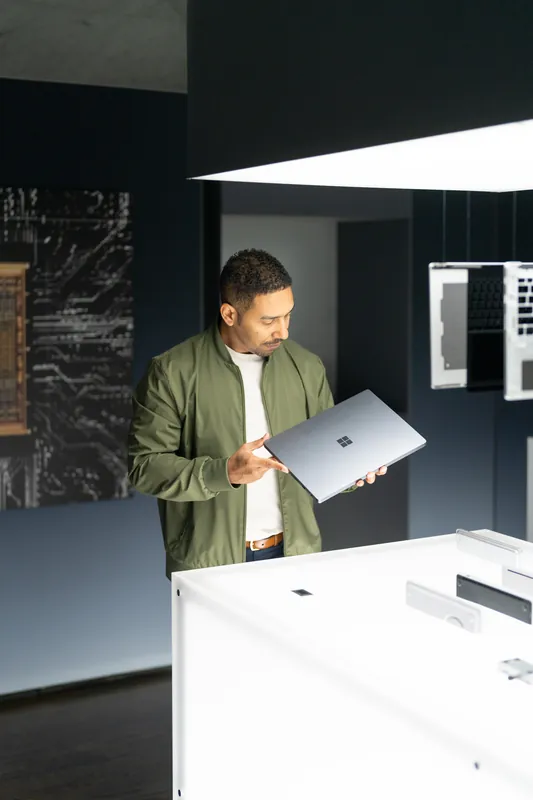 A guest holding a Surface laptop beneath the gallery's overhead light panel.