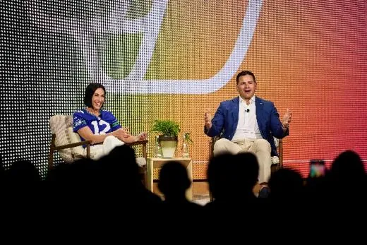 Two guests in conversation on the main stage against a bright patterned backdrop.