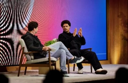 A panel seated on stage in front of the summit's op-art wall.