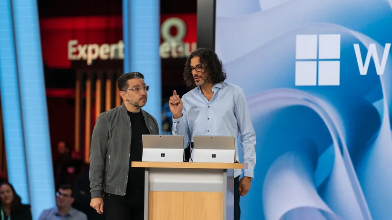Two presenters on stage in front of the Windows backdrop.