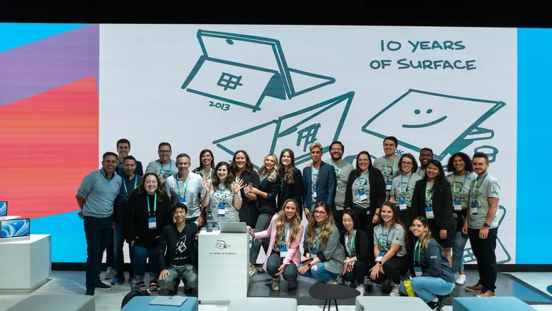 A group photograph in front of the Ten Years of Surface wall.